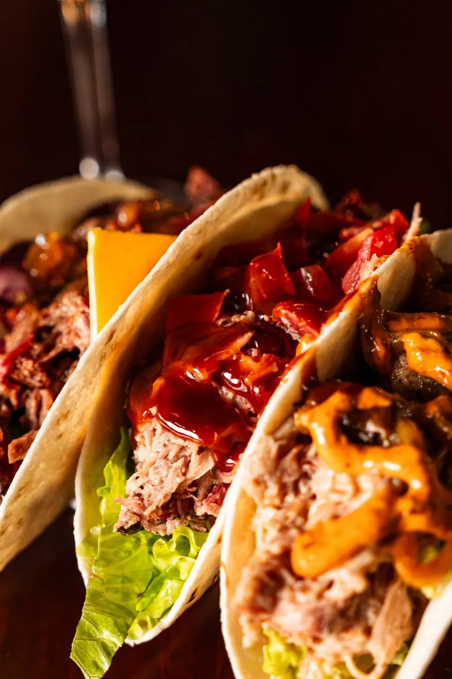 Tre tacos farciti con pulled pork, cheddar, peperoni e salsa